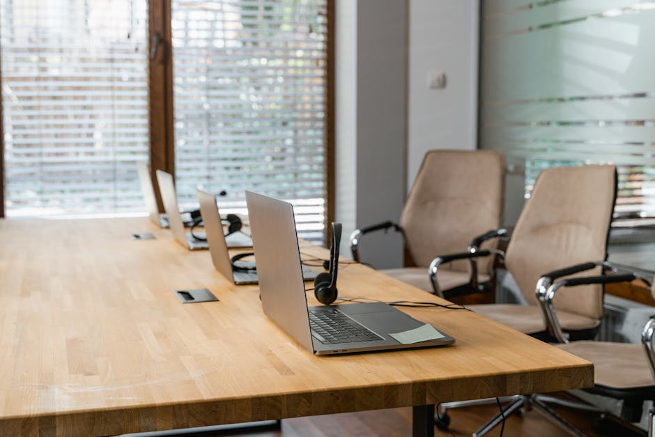 A call center office setup with laptops, headphones, and wooden tables in a modern interior.
