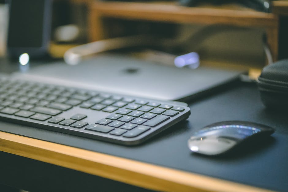 A sleek office setup featuring a wireless keyboard, mouse, and laptop on a desk