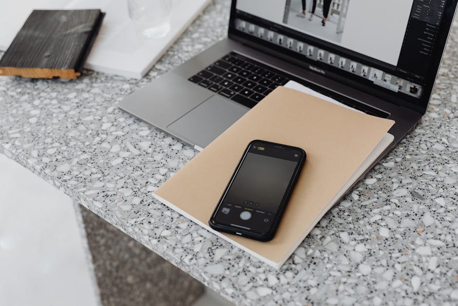 A stylish workspace featuring a laptop and smartphone on a marble surface, ideal for tech and business themes
