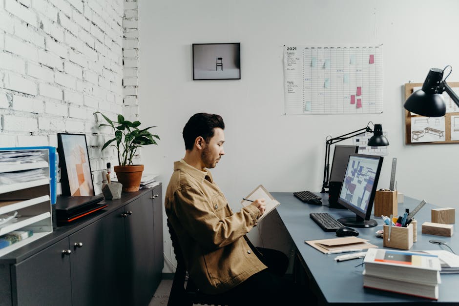 Young man in a brown jacket working at a computer in a stylish, modern office