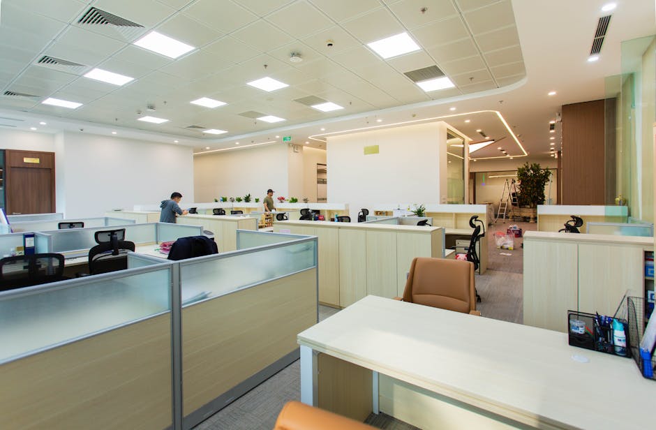Bright and spacious office interior featuring open-plan cubicles, modern furniture, and ceiling lights