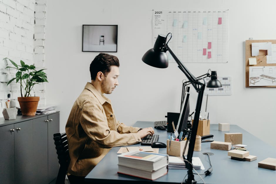 Man working at a computer in a modern office setting with organized workspace.